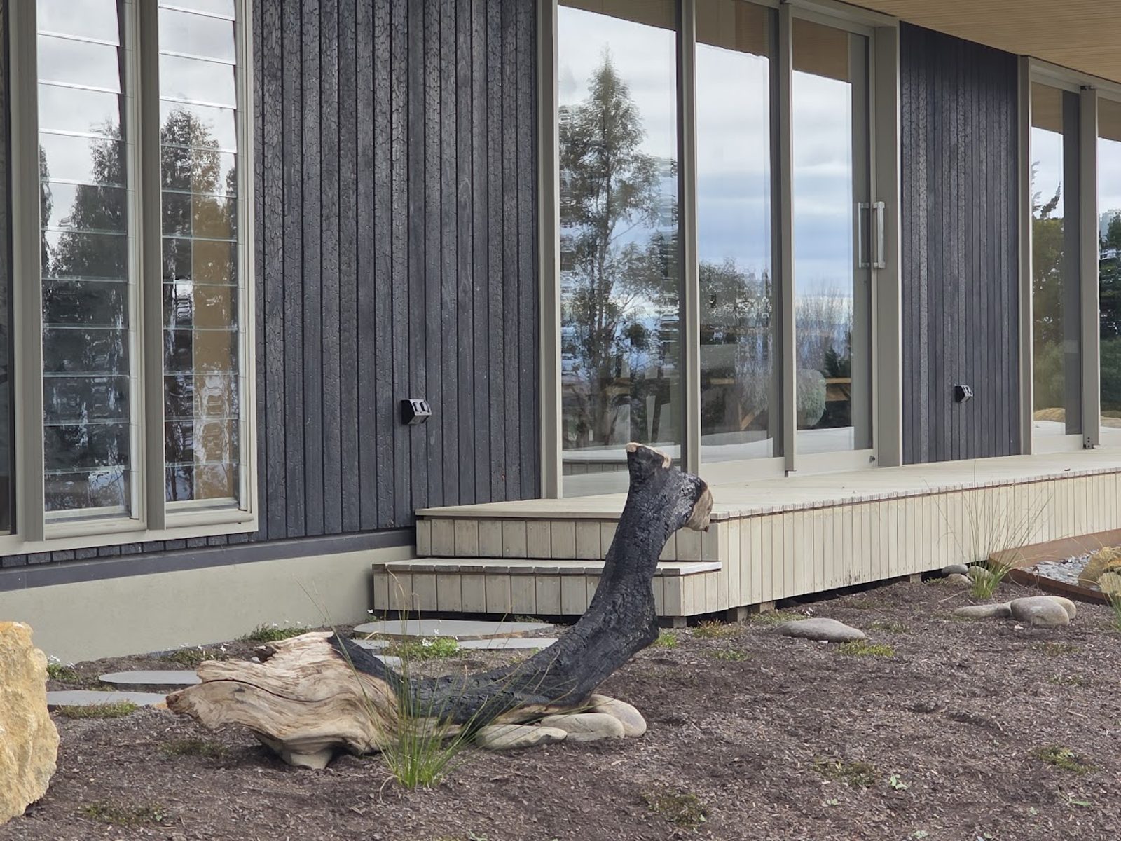 Charred log set against the shou sugi ban cladding at Black Beach House